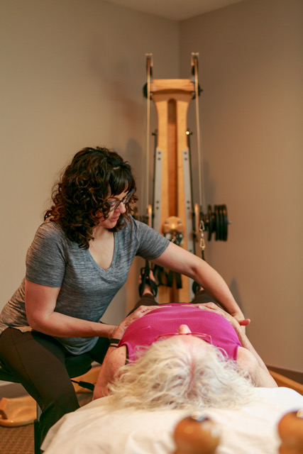 A licensed GYROTONIC® Trainer working with a client on a Pulley Tower Combination Unit